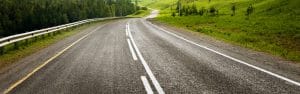 Scenic open road winding through green countryside representing vehicle transport routes by Open Road Carriers